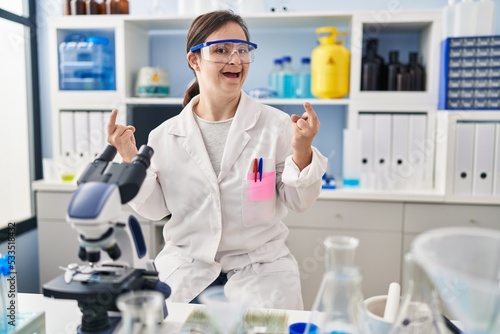 Hispanic girl with down syndrome working at scientist laboratory showing middle finger doing fuck you bad expression  provocation and rude attitude. screaming excited