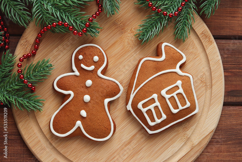 Gingerbread man and house cookies with Christmas tree branches on the wooden board. Christmas festive composition. Top view, flat lay