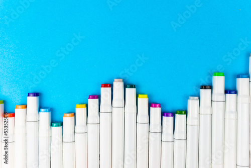 Many white assorted markers stacked on a blue background. Place for writing. Copy space