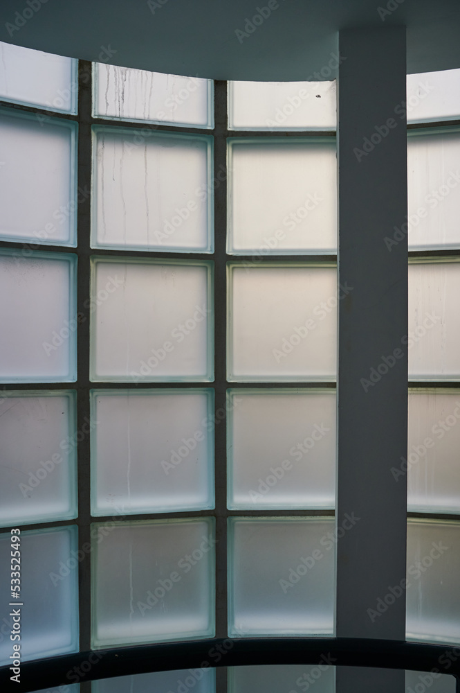 Interior of building looking at opaque of curved window constructed from glass blocks during daytime Interior of building looking at opaque of curved window constructed from glass blocks during daytime