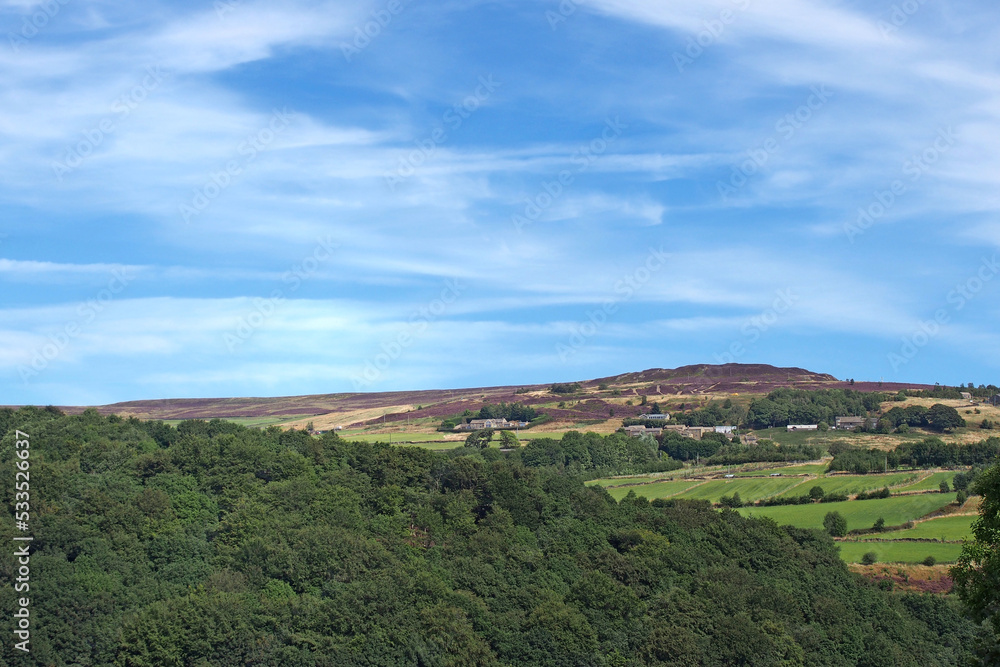 view of the village of midgley moor surrounded by farmhouses and pennine countryside in summer sunlight