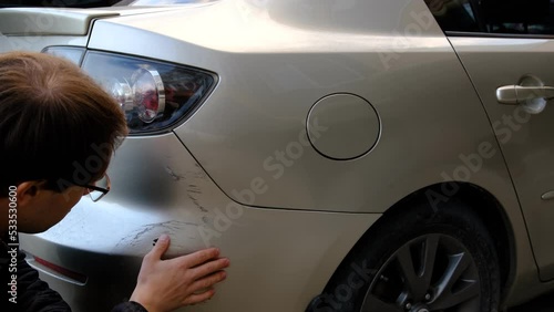 View of a Young man after car crash looking for scratches on his car and take photos of damage. Car damage, car crash concept,