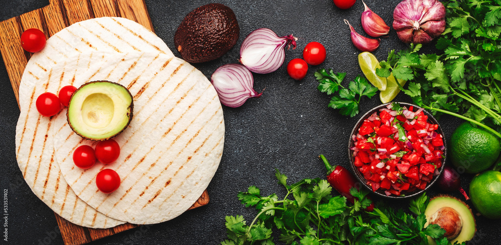 Mexican food. Spicy salsa sauce with tomatoes, chili peppers, onion, garlic and cilantro with corn tortilla, black table background, top view Mexican food. Spicy salsa sauce with tomatoes, chili peppers, onion, garlic and cilantro with corn tortilla, black table background, top view