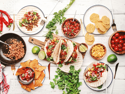 Taco party. Served table with tortillas, nachos, sauces, appetizers and plates. Homemade mexican food cooking scene. White table background, top view