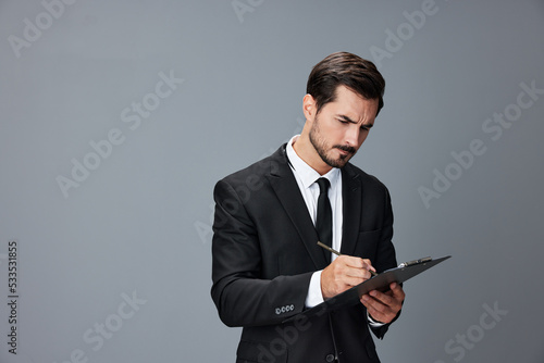 Portrait of a business man in a stylish suit smile with teeth hands up handsome face on gray isolated background with tablet in hand. Business concept young businessman startup copy space.