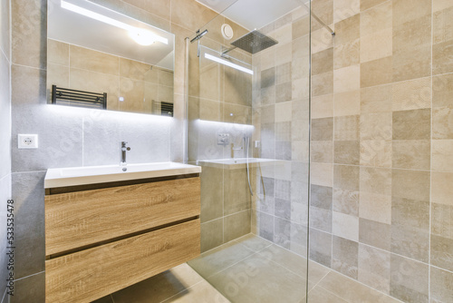 Sinks with mirrors and shower box with glass door in modern bathroom with white tiled walls photo