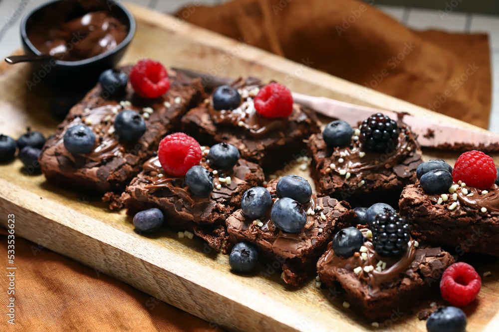 Brownie with berries and chocolate on a wooden board. Homemade vegan brownies. Brownie with berries and chocolate on a wooden board. Homemade vegan brownies.