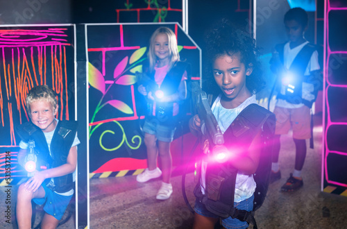 Teenager girl with laser pistol in her hands playing laser tag game