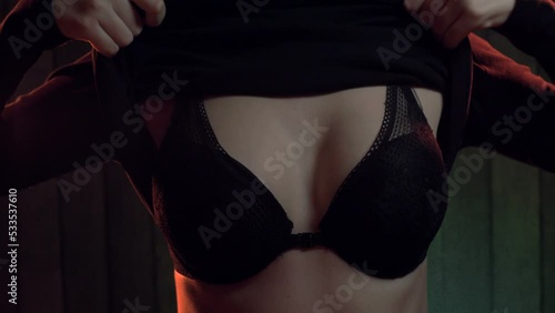  Close up of woman`s chest in black lingerie, undressing at home photo