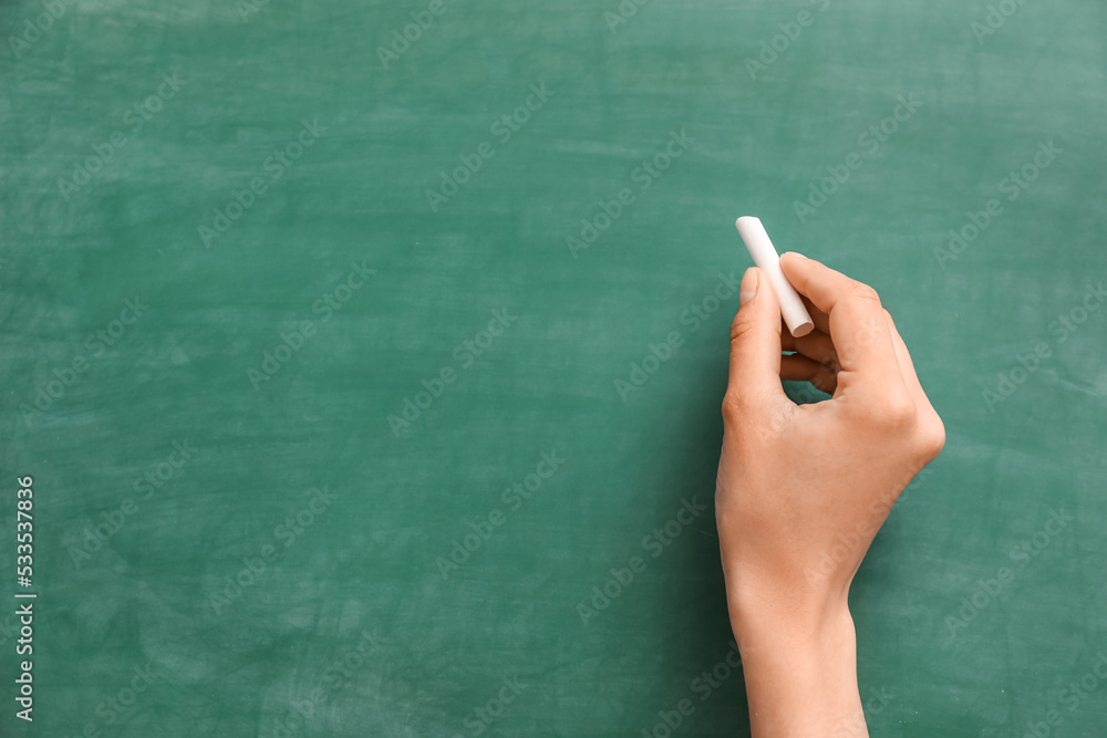 Naklejka premium Female hand with chalk against green blackboard
