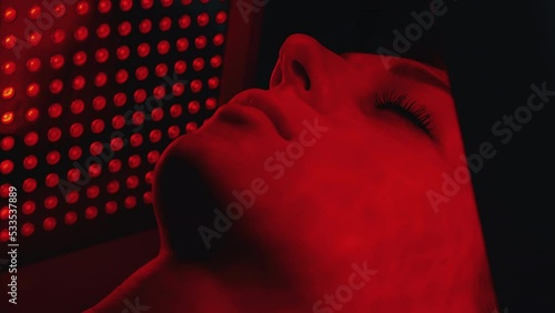 LED red light is treating the facial skin of a young woman.