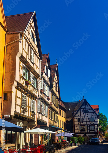 View of historic center of French city of Colmar with paved streets and picturesque half-timbered houses painted in traditional Alsatian colors in summer