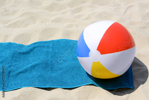 Blue towel and colorful beach ball on sand