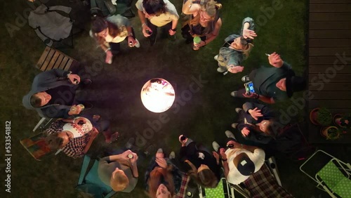 Bird's eye view of young adults dancing at a garden party around a firebasket photo