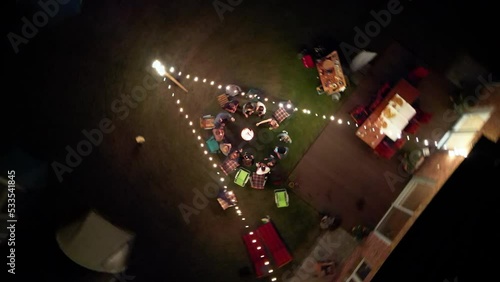 Bird's eye view of young adults dancing at a garden party around a firebasket photo