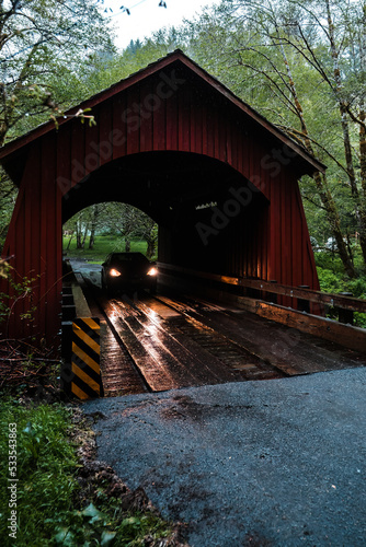 Car headlights shining on a covered bridge deep in the forest.