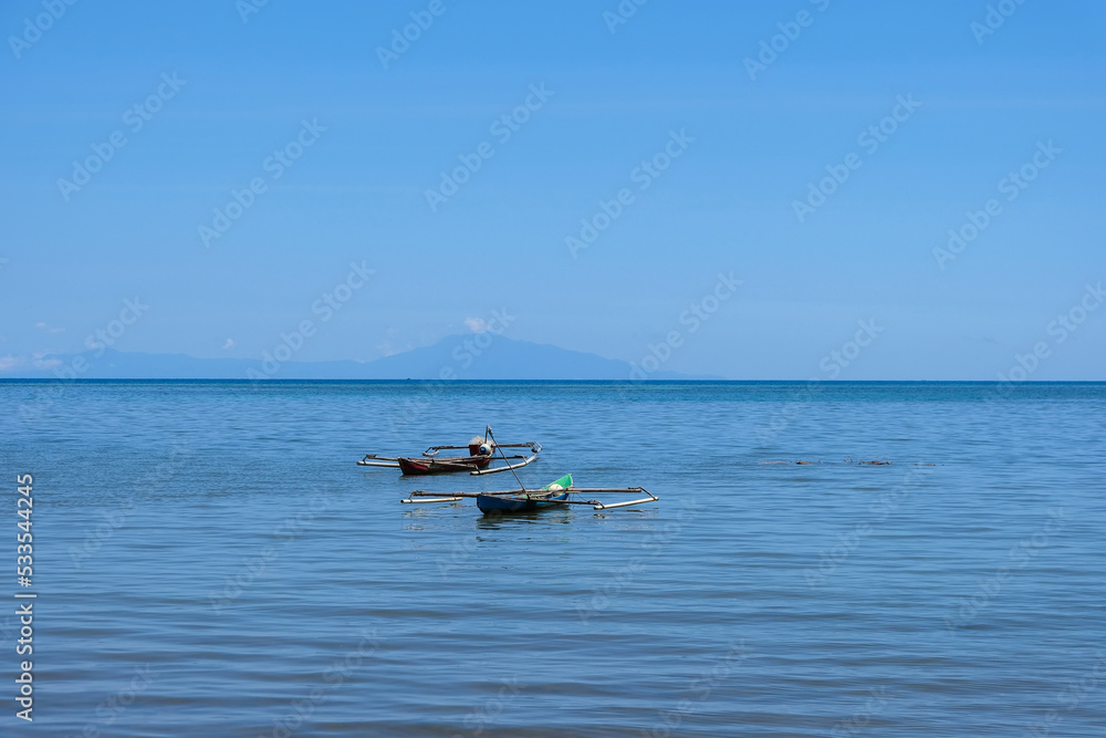 Two traditional wooden fishing canoes in the shallows of blue ocean on a remote tropical island