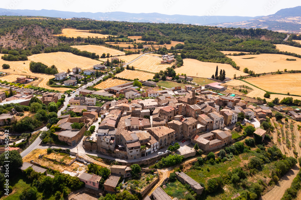 Picturesque drone view of small medieval township of Figuerola d Orcau in Spain on background of vaste golden agricultural fields on summer day