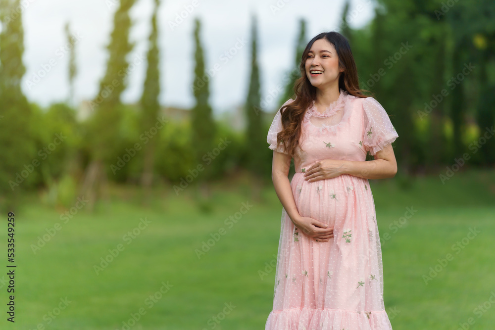 cheerful pregnant woman standing in park cheerful pregnant woman standing in park