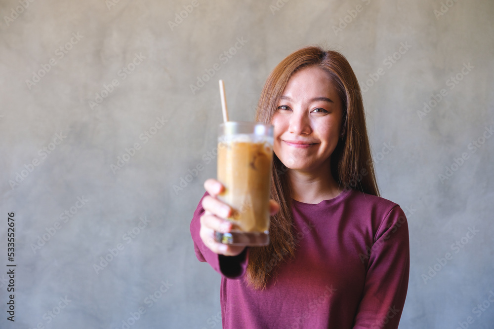 Portrait image of a young woman holding and serving a glass of iced coffee Portrait image of a young woman holding and serving a glass of iced coffee