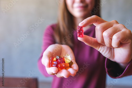 Closeup image of a young woman holding and showing at a red jelly gummy bears photo