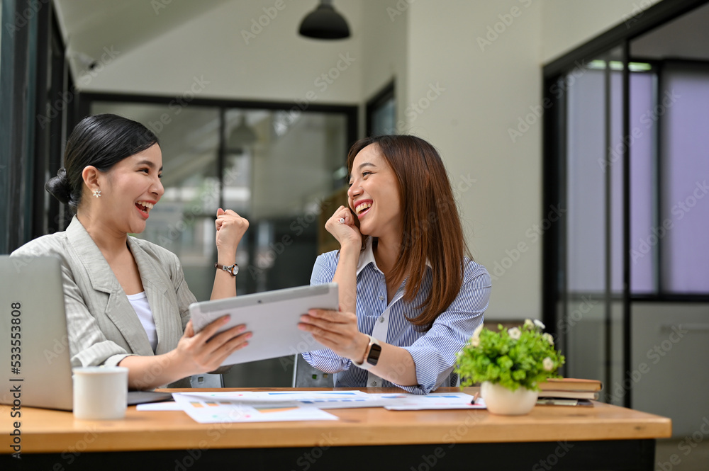 Two happy and surprised millennial Asian businesswomen celebrate their success together Two happy and surprised millennial Asian businesswomen celebrate their success together
