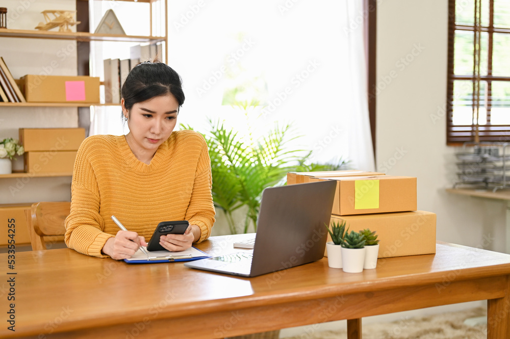 Asian female online small business owner concentrated working on her business Asian female online small business owner concentrated working on her business