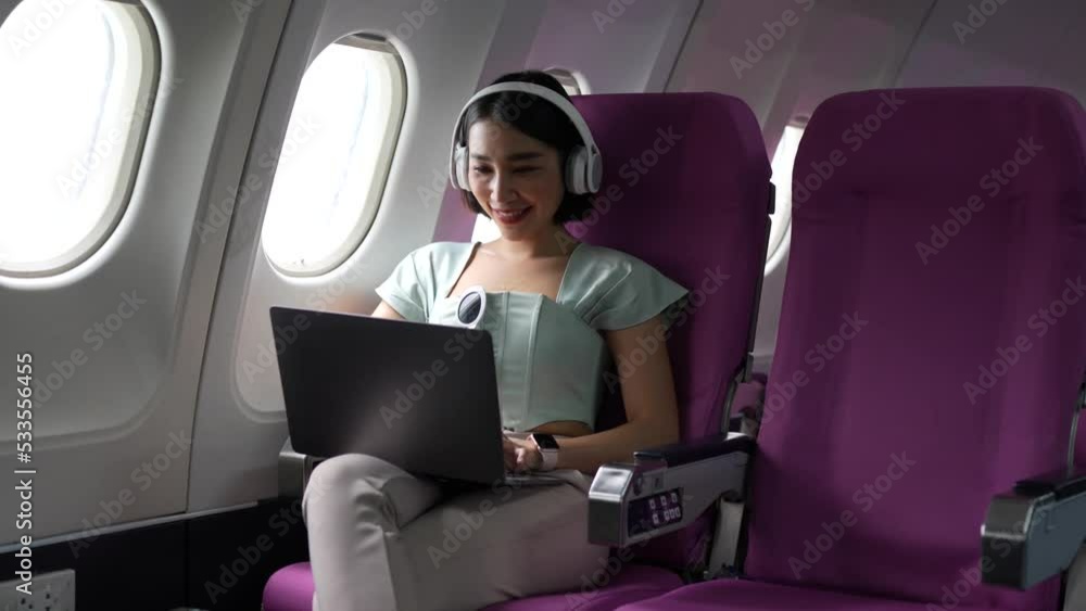 Joyful asian woman sits in the airplane and using mobile phone while go to travel Joyful asian woman sits in the airplane and using mobile phone while go to travel