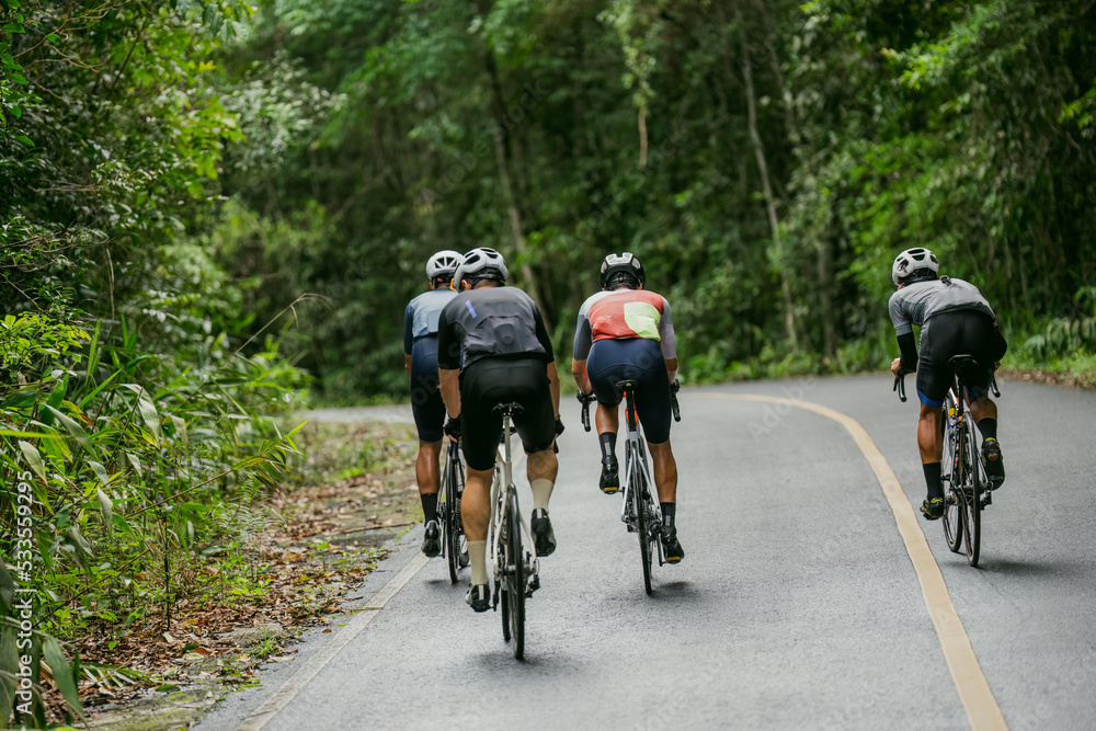 Groups of cyclists riding road bikes in the morning are climbing.