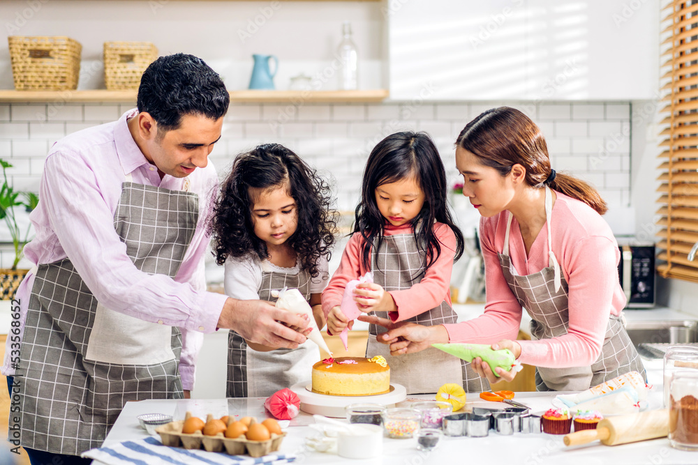 Portrait of enjoy happy love asian family father and mother with little asian girl daughter child play and having fun cooking food together with baking cookie and cake ingredient in kitchen