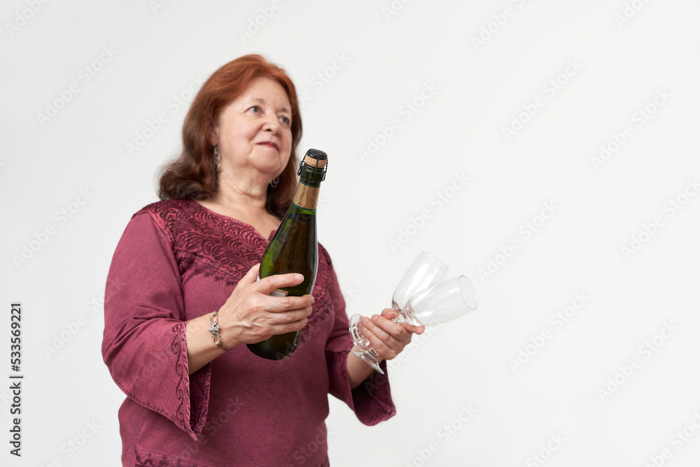 Hispanic mature woman smiling while holding a bottle of champagne or cider and a pair of glasses. Concept of celebratory toast. Selective focus composition with copy space. Hispanic mature woman smiling while holding a bottle of champagne or cider and a pair of glasses. Concept of celebratory toast. Selective focus composition with copy space.