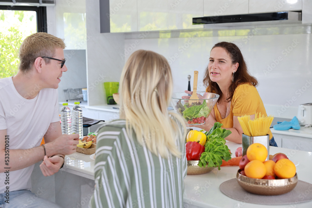 Group of happy family or friends with different ages enjoy eating breakfast or dessert with salad, donus, fruit, and soft drink in kitchen room at home. Happiness and healthy lifestyle concept.
