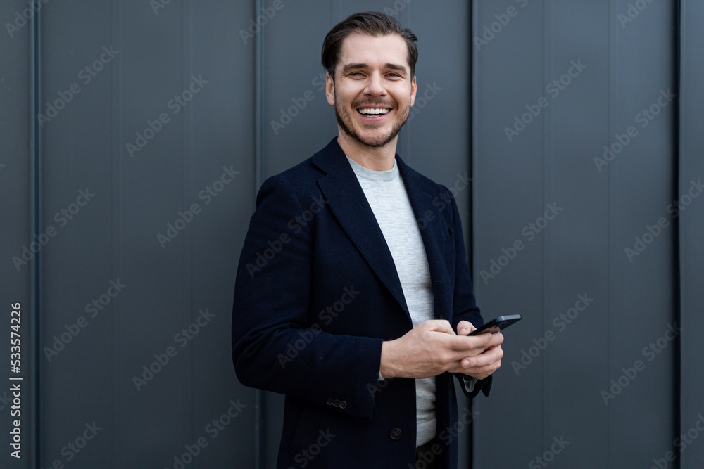 portrait of a strong middle-aged businessman using a mobile phone and a wide smile against a gray wall portrait of a strong middle-aged businessman using a mobile phone and a wide smile against a gray wall