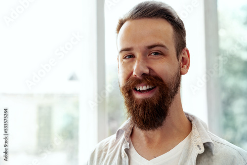 Bearded smiling handsome young man standing alone at home