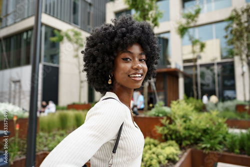 Portrait of young african woman with afro hairstyle smiling in urban background