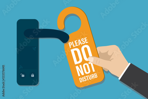 Hotel guest hangs Do not disturb sign on hotel room door handle. Hanger style paper or plastic tag with text for room service privacy, hang label. Privacy for leisure or business negotiations.