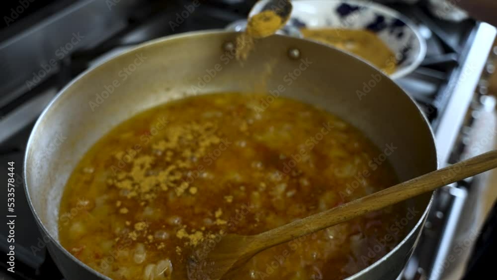Spices Being Added To Simmering Curry Sauce From Spoon Into Large Pot. Slow Motion Spices Being Added To Simmering Curry Sauce From Spoon Into Large Pot. Slow Motion