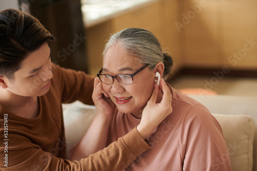 Boy Helping Grandmother to Put in Earbuds