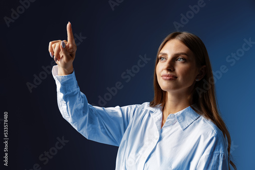 Foto Young female entrepreneur touching virtual screen against grey studio background