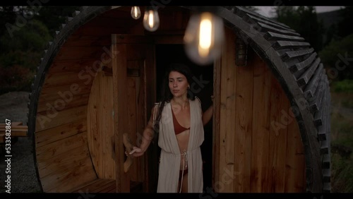 Young attractive female walking out of barrel sauna
