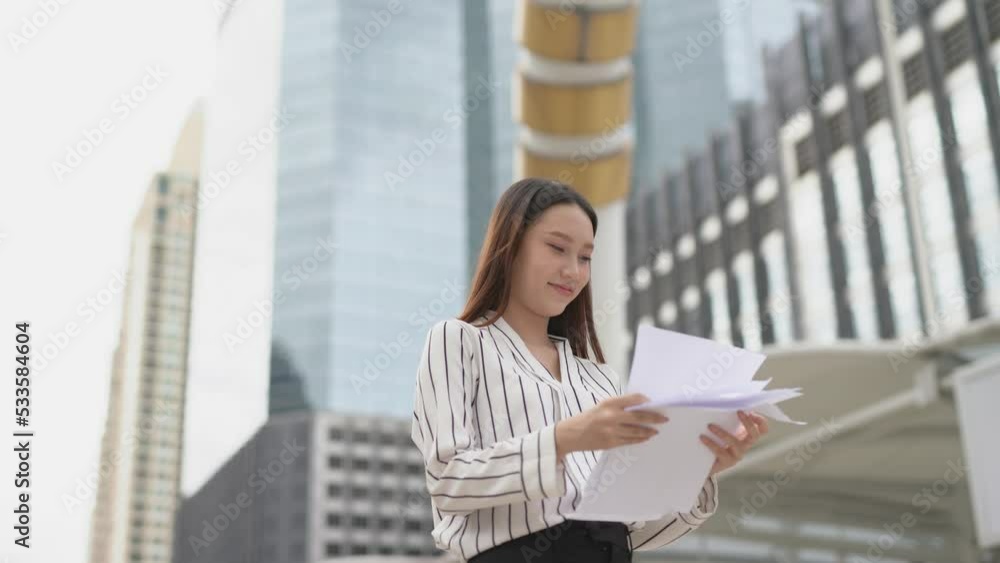 4K video of a young asian beautiful businesswoman lady care free and throw away a pile stack of document paper in a central business district in Bangkok 4K video of a young asian beautiful businesswoman lady care free and throw away a pile stack of document paper in a central business district in Bangkok