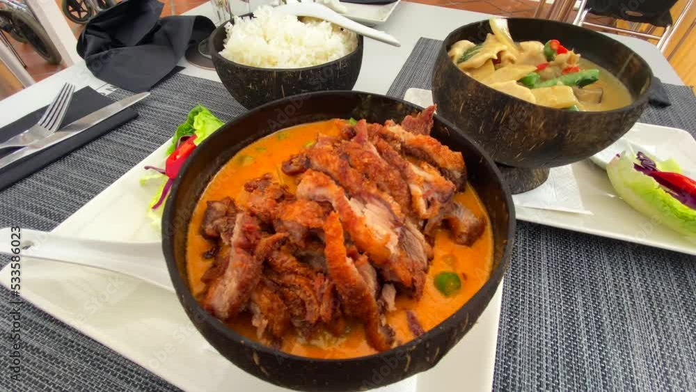 Traditional thai red curry crispy duck dish and green curry chicken with rice in coconut bowls, tasty Thai cuisine restaurant, 4K shot Traditional thai red curry crispy duck dish and green curry chicken with rice in coconut bowls, tasty Thai cuisine restaurant, 4K shot