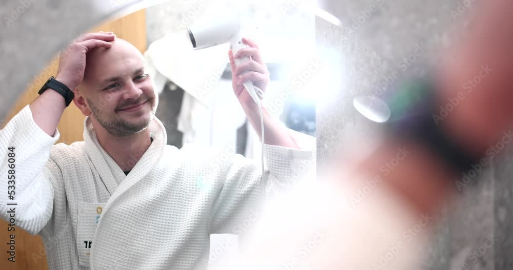 Bald man drying his hair with hairdryer in front of mirror 4k movie slow motion Bald man drying his hair with hairdryer in front of mirror 4k movie slow motion