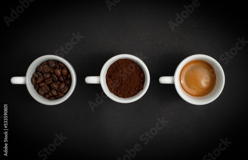 Three white cups with coffee on a black background. Coffee beans, ground coffee, black espresso coffee.