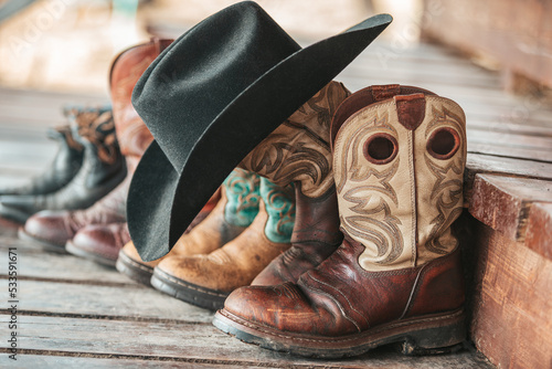 Western boots and black felt hat. Working cowboy boots on the background of brown wooden steps.