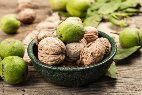 Ripe brown and unripe green walnuts in a bowl