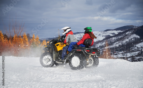 Portrait of man and woman riding on offroad four-wheeler ATV. Concept of active leisure and winter activities.