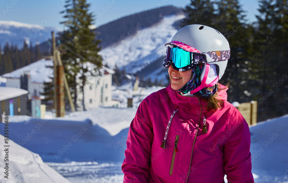 Woman snowboarder with equipment helmet and goggles outwear holding snowboard resting on top of ski slope in sunlight. Mountain's top in sunny winter day Carpathians. Ukraine. Free space for you text