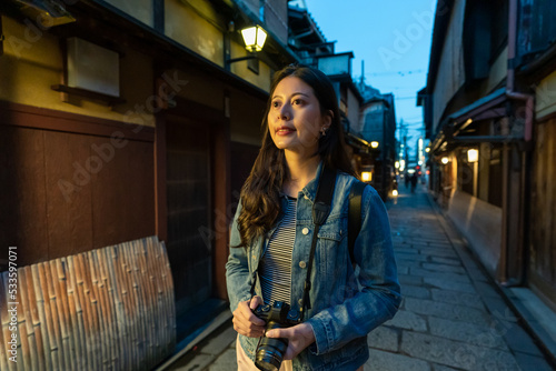 amazed asian Japanese girl photographer looking at local geisha houses while exploring hanamikoji street in gion Kyoto japan at night photo