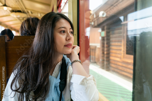 asian Japanese woman passenger propping face and looking out of window as the Arashiyama Mountains sagano romantic old train departing from the platform in Kyoto japan photo